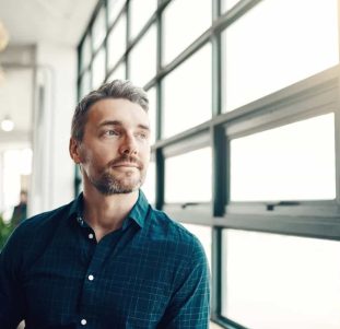 Shot of a mature businessman looking thoughtfully out of an office window