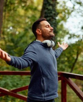 Mid adult man with arms outstretched outdoors